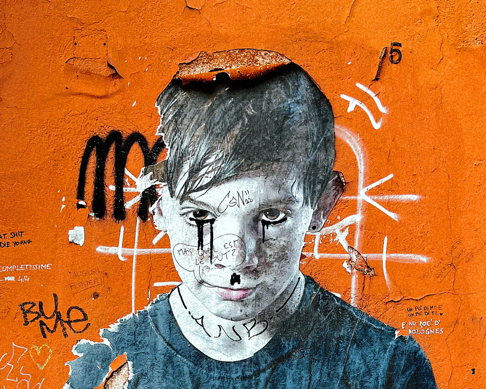 Street art in Bologna of a boy's face against an orange background