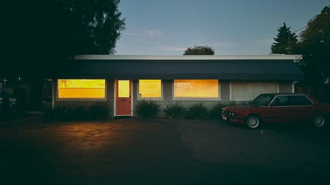 A glow of light from inside a small building. BMW parked out front.